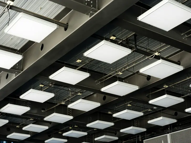 Rows of square ceiling light fixtures under an exposed steel ceiling